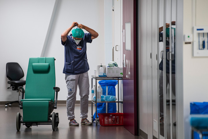 Egészségügyi dolgozó veszi fel a maszkját egy stockholmi kórházban, mielőtt belépne a koronavírussal fertőzött betegeket kezelő osztályra 2020 júniusábanFotó: Jonathan Nackstrand / AFP