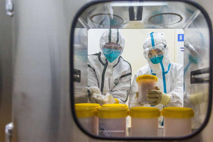 A kínai betegségmegelőzési és járványvédelmi központ pekingi laboratóriumának kutatói átveszik a SARS–CoV–2 koronavírus mintáit 2020. február 25-én – Fotó: Liu Peicheng / Xinhua / AFP