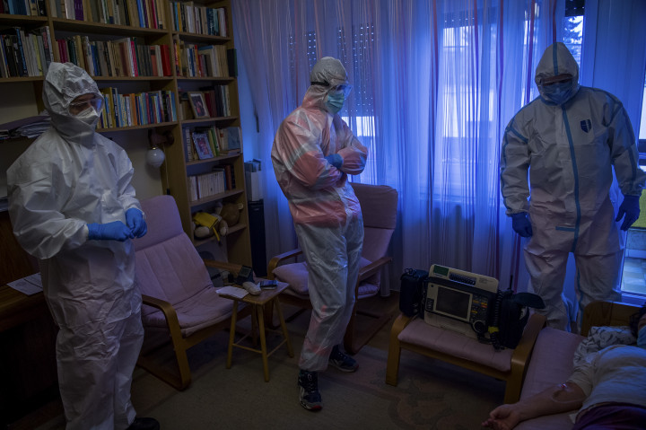 Védőruhát viselő mentők egy koronavírussal fertőzött beteget látnak el otthonában