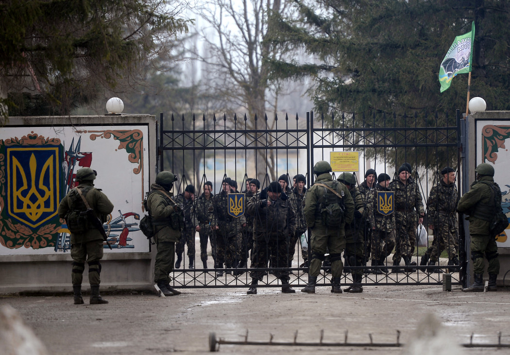 Orosz és ukrán katonák beszélnek egy ukrán katonai egység kapujában a Szimferopol melletti Perevalnoye faluban, a Krím félszigeten 2014. március 20-án – Fotó: Filippo Monteforte / AFP